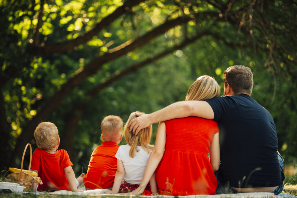 Famille de quatre personnes marchant ensemble dans un parc verdoyant pendant un week-end en plein air