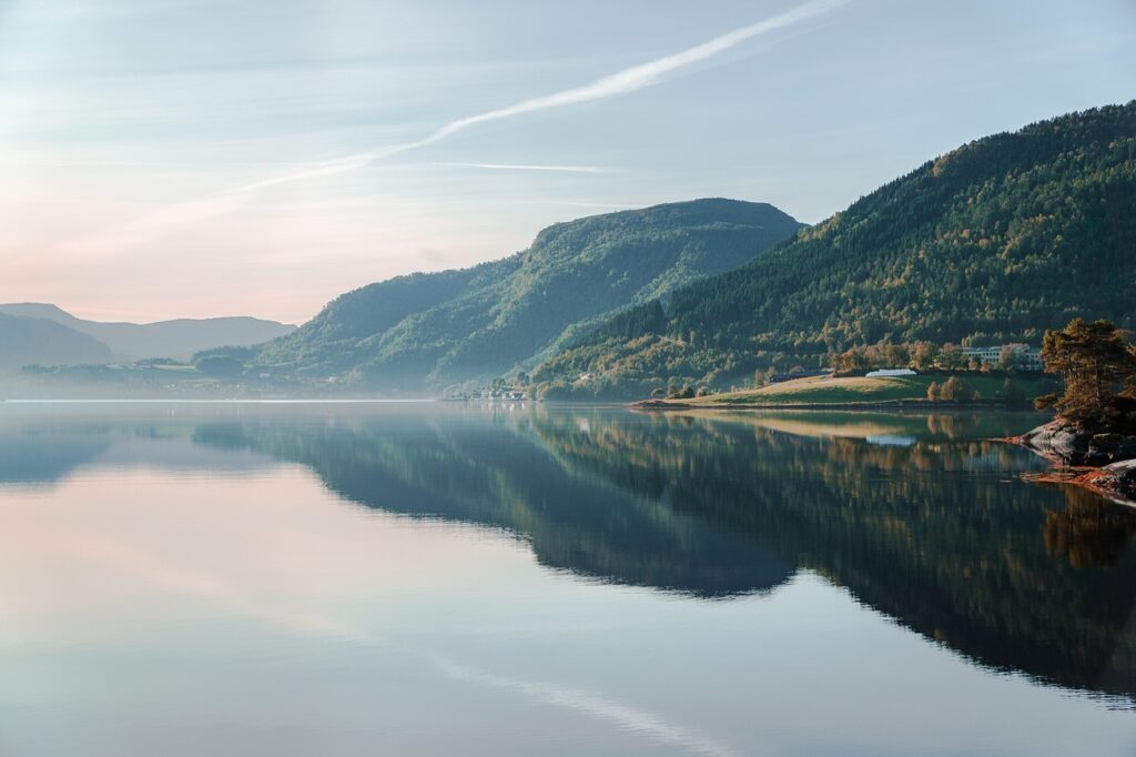 Paysage scandinave avec lac paisible, forêts et montagnes au lever du jour