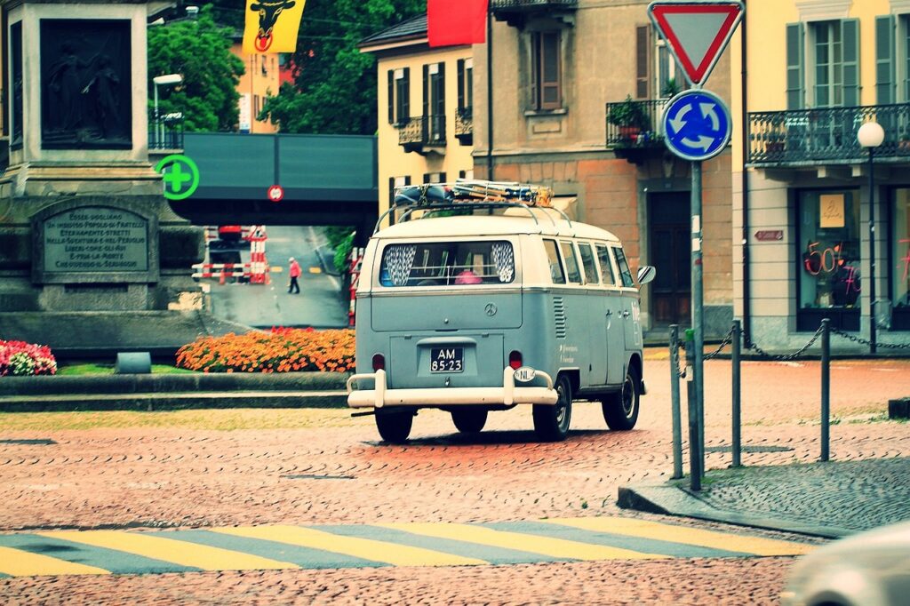 Van aménagé vintage traversant une ville, symbole de voyage en famille libre et économique
