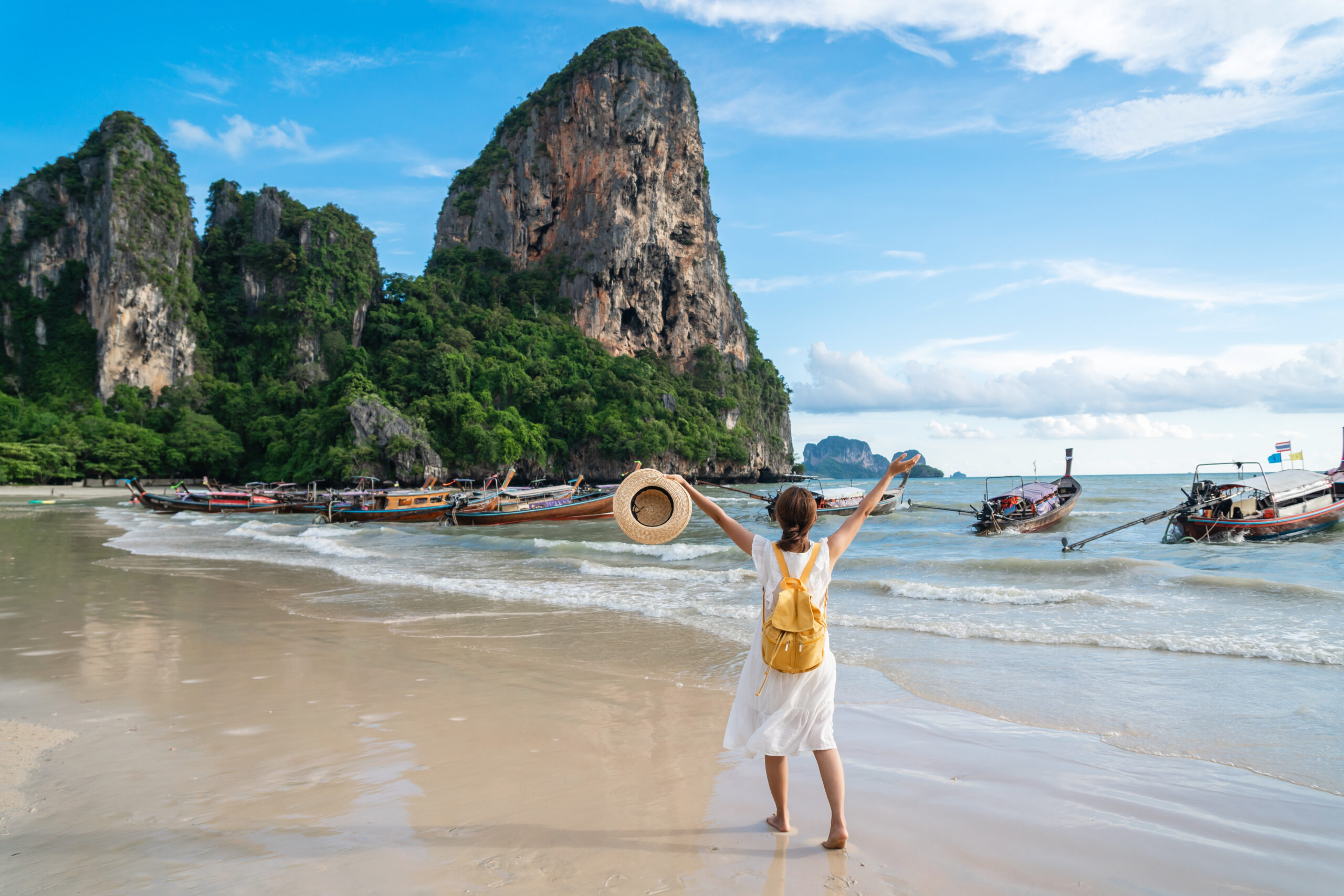 Plage tropicale d’Asie avec falaises karstiques, bateaux traditionnels et ciel bleu, destination abordable en 2025