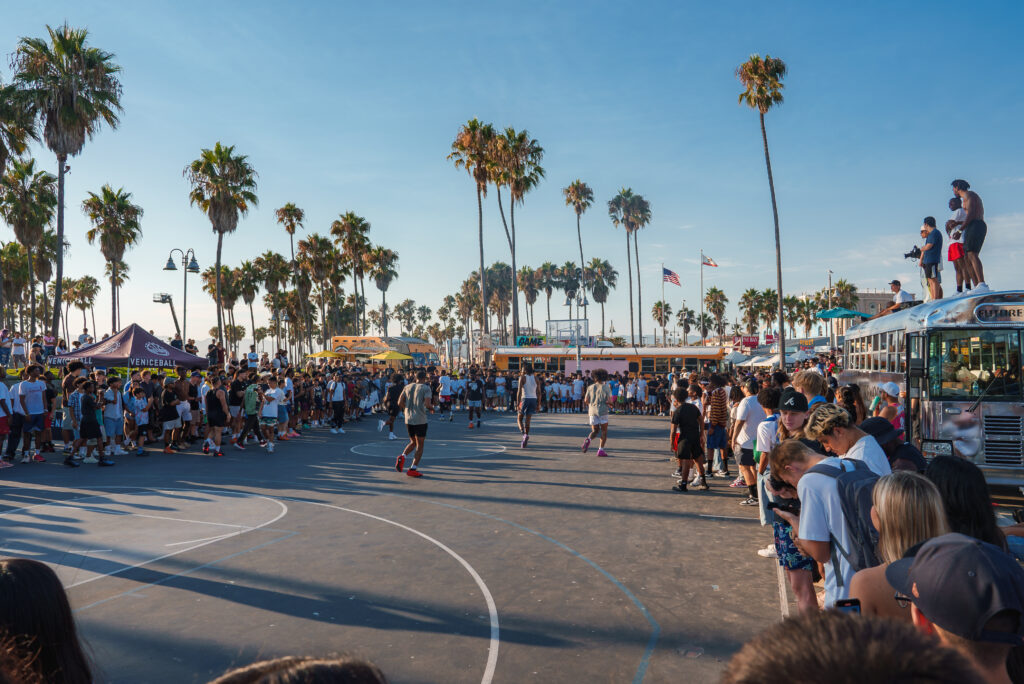 Match de basket animé à Venice Beach, Los Angeles, avec palmiers et foule lors d’un road-trip dans l’Ouest Américain pas cher