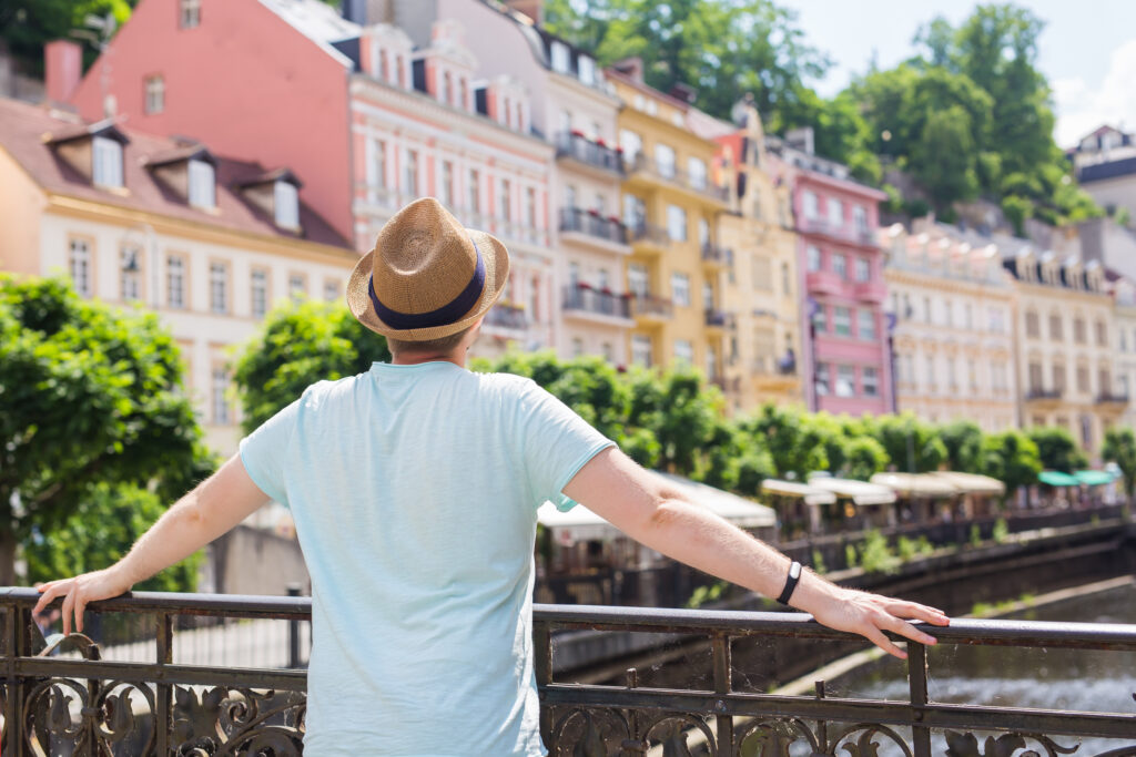 Voyage pas cher en Europe, touriste admirant une ville pittoresque depuis un pont