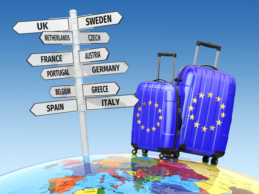 Voyager hors saison, valises prêtes devant panneau de destinations en Europe