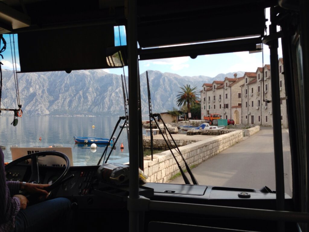 Vue depuis un bus en Andalousie avec les montagnes et un village en bord de mer, symbole d’un itinéraire économique entre Séville, Cordoue et Grenade.