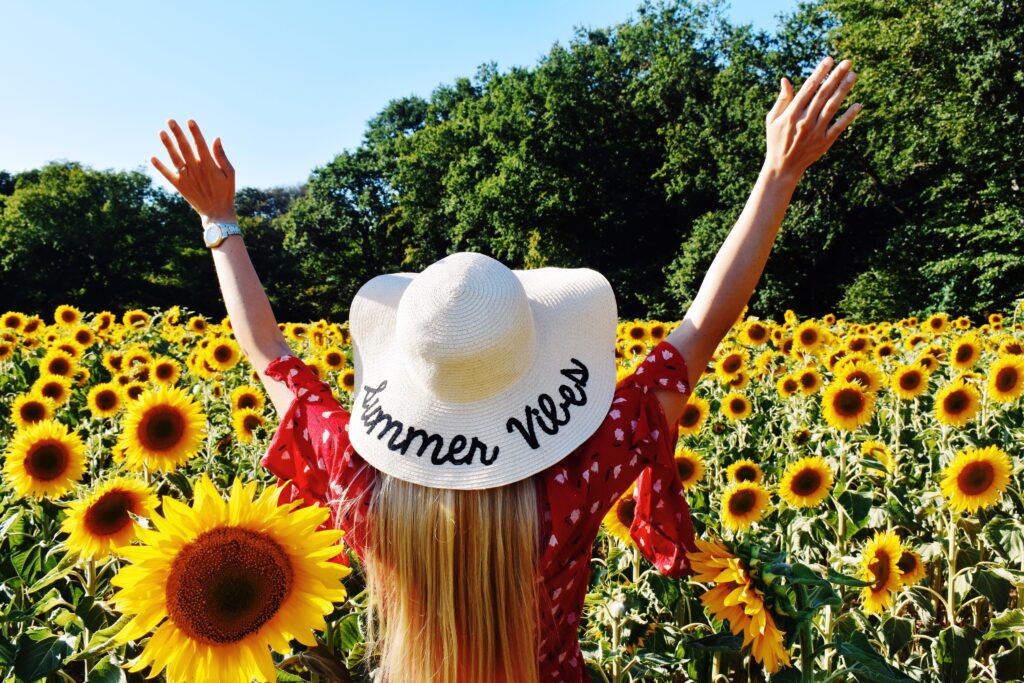 Où partir en avril — 15 destinations idéales pas chères : voyageuse bras levés dans un champ de tournesols
